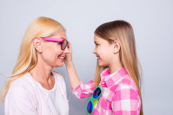 Close up side profile photo funky two people blond hair she her granny little granddaughter ready holiday celebrate look eyes wear specs pink plaid checkered shirt sweater isolated grey background - 写真・画像