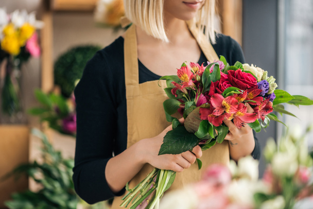 Cropped view of florist in apron holding bouquet in flower shop - Foto, immagini