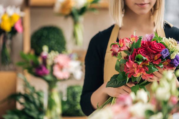 Вид на флориста в фартуке, держащего букет в цветочном магазине
 - Фото, изображение