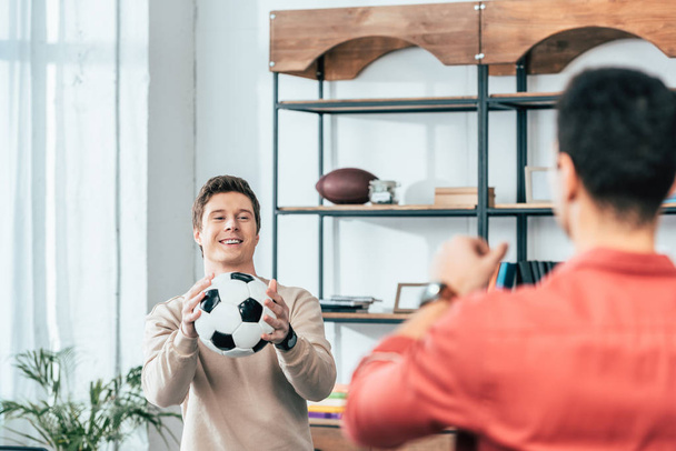 Two smiling friends playing with football ball at home - Photo, Image