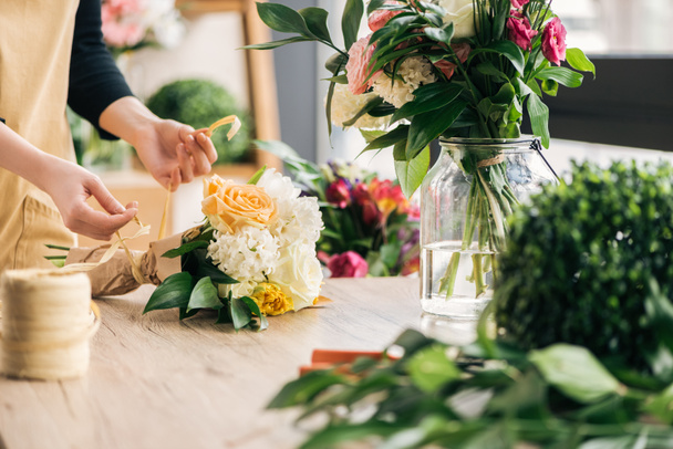 Partial view of florist making bouquet in flower shop - Foto, afbeelding