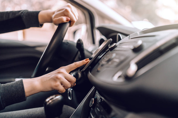 Close up de mulher grávida caucasiana dirigindo carro e ligando GPS no telefone inteligente. Outra mão no volante
. - Foto, Imagem