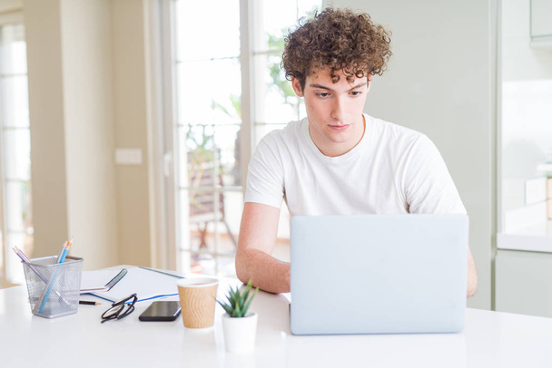 Молодой студент работает и учится с помощью компьютера ноутбука с уверенным выражением на умном лице, думая серьезно
 - Фото, изображение