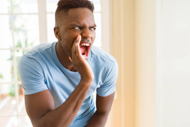 African american man shouting with rage, yelling excited with hand on mouth - Foto, Imagen