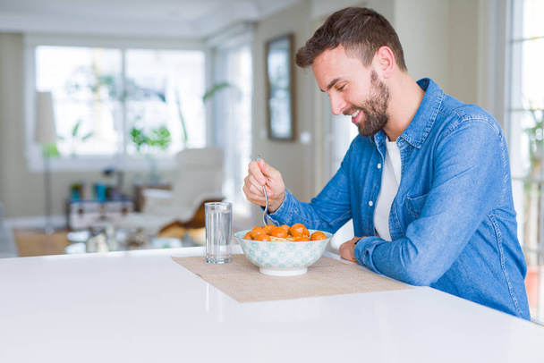 Pohledný muž, jíst těstoviny s masové kuličky s rajskou omáčkou na hom - Fotografie, Obrázek