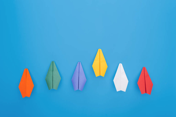 Flat lay with colorful paper planes on blue surface - Foto, Imagen