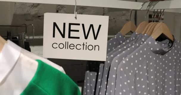 Nowy znak kolekcji w sklepie ubrania z wieszakami - Materiał filmowy, wideo