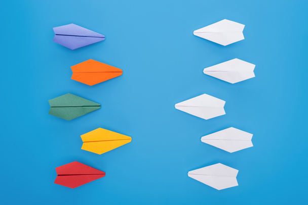 Tasainen lay värikkäitä paperin lentokoneita sinisellä pinnalla
 - Valokuva, kuva