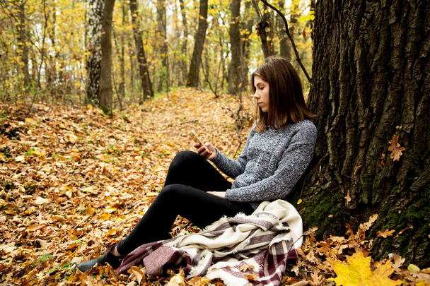 Jeune belle fille dans une veste grise assis à l'automne avant
 - Photo, image