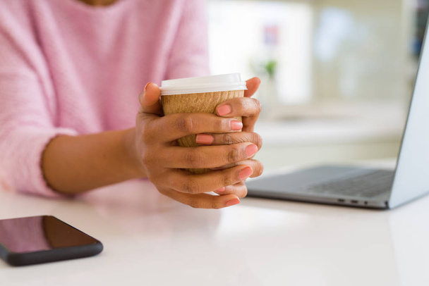 Close up of young woman drinking a coffee while working using laptop - Fotoğraf, Görsel