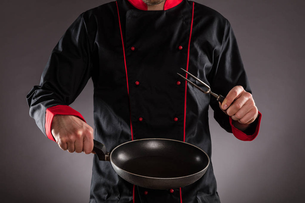 Closeup of chef holding empty frying pan and fork - Foto, Imagen