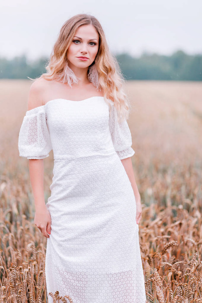 小麦の背景にポーズをとって白いドレスを着た花嫁 - 写真・画像