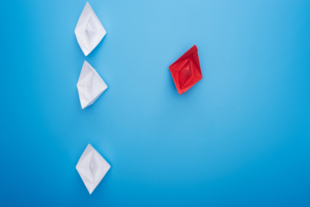 Colocación plana con barcos de papel blanco y rojo sobre superficie azul
 - Foto, Imagen