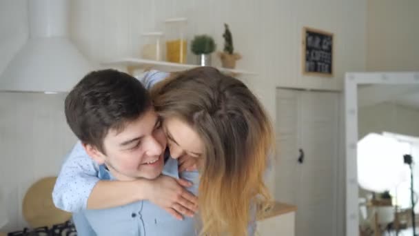 girl jumped on guy shoulders laughing kissing man in kitchen - Filmagem, Vídeo
