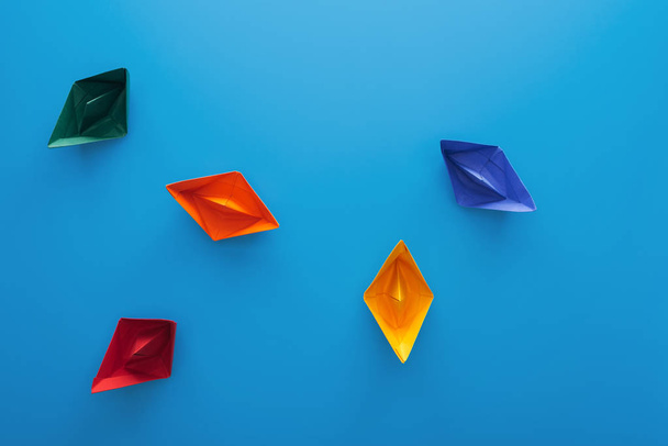 Top view of colorful paper boats on blue surface - Photo, Image