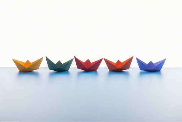 Barcas de papel de colores sobre superficie clara sobre fondo blanco
 - Foto, Imagen