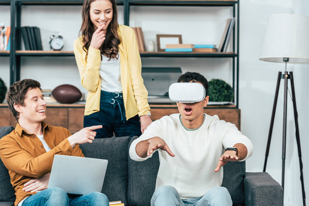 Three laughing friends using vr headset in living room - Photo, Image