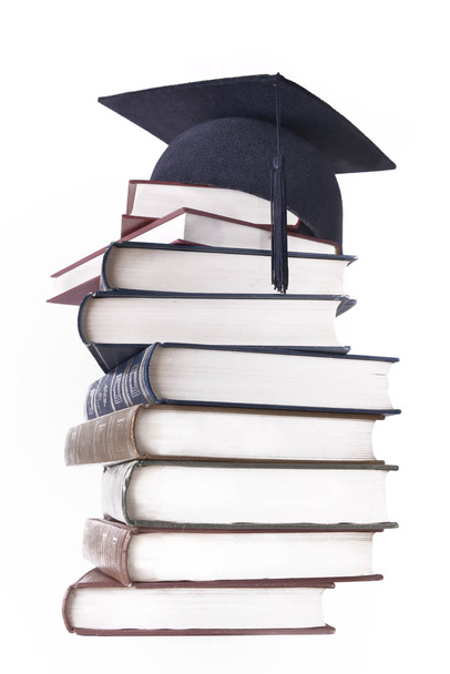 φοιτητής μαύρο καπάκι βάλει βιβλία στοιβάζονται απομονωθεί σε λευκό φόντο  - Φωτογραφία, εικόνα