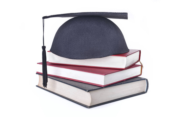 φοιτητής μαύρο καπάκι βάλει βιβλία στοιβάζονται απομονωθεί σε λευκό φόντο  - Φωτογραφία, εικόνα