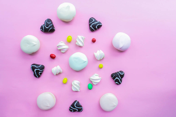 marshmallows, peperkoek en snoep zijn geordend in een cirkel op een roze achtergrond, bovenaanzicht. snoep in een cirkel - Foto, afbeelding