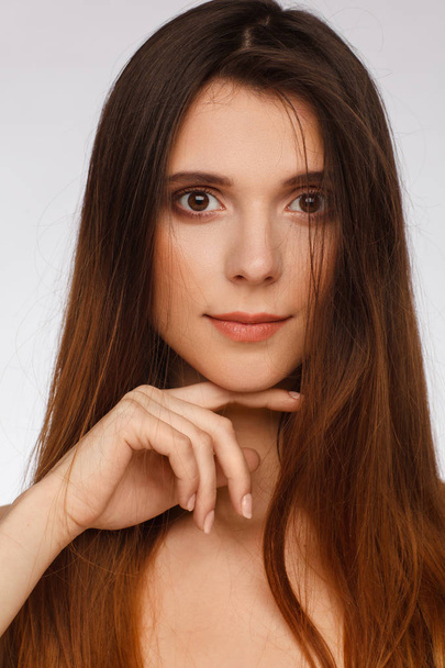 Portrait of a beautiful woman with straight long hair and interesting emotion. Light gray background - Foto, Imagem