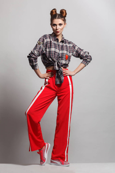 Uma foto de um modelo divertido e positivo vestindo uma camisa xadrez, calças de camisola vermelhas e tênis. Sessão de fotos estúdio
 - Foto, Imagem