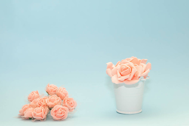 Ροζ ροδοπέταλα σε ένα παιχνίδι λευκό κουβά δίπλα από λουλούδια σε ανοιχτό μπλε φόντο, λουλούδια για την αργία της 8 Μαρτίου ή 14 Φεβρουαρίου, ημέρα της γυναίκας - Φωτογραφία, εικόνα