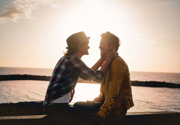 幸せなゲイ カップル デート次ビーチ アット サンセット - 若いレズビアンの女性を屋外 - 入札のロマンチックな瞬間を持っている Lgbt、同性愛愛とライフ スタイルの関係概念 - 写真・画像