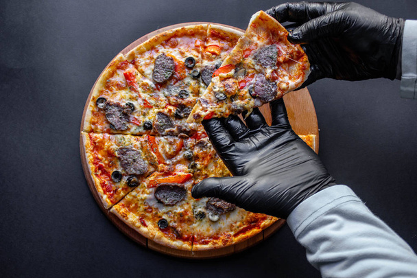 Nuoret ottavat viipaleita herkullista pizzaa pahvilaatikosta pöydällä
 - Valokuva, kuva