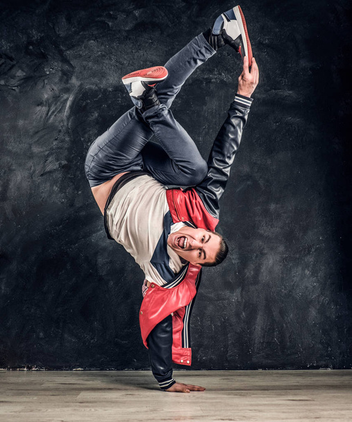 Emotionele stijlvol geklede man uitvoeren van breakdance beweegt op de vloer. - Foto, afbeelding
