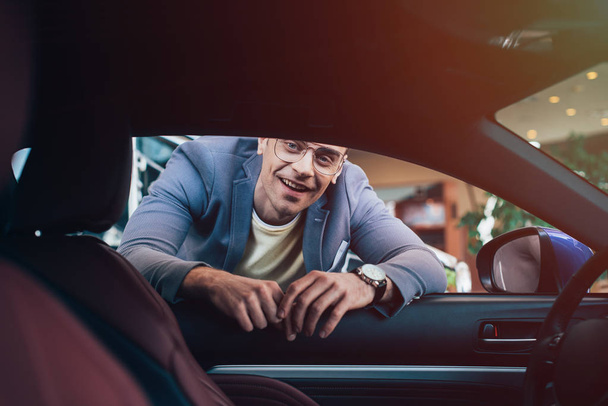 selective focus of happy man in glasses looking in car - Photo, image