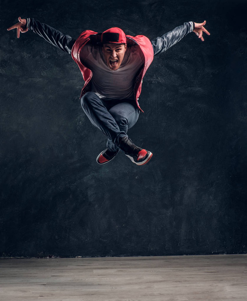 Emotionele stijlvol geklede man uitvoeren van breakdance springen. - Foto, afbeelding