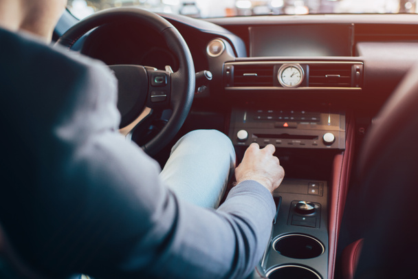 cropped view of man sitting in modern automobile and holding manual transmission - Foto, imagen