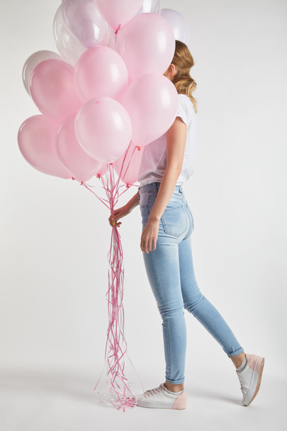 girl in casual clothes covering face with festive pink air balloons on white - Valokuva, kuva