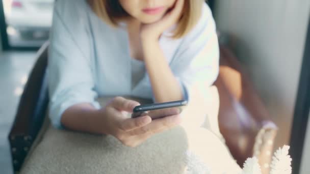 Mujer asiática freelance de negocios que utiliza el teléfono inteligente para hablar, leer y enviar mensajes de texto mientras está sentado en la mesa en la cafetería. Estilo de vida mujeres hermosas inteligentes que trabajan en los conceptos de cafetería
. - Metraje, vídeo