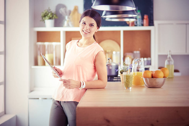 Beautiful young woman using a digital tablet in the kitchen. - Foto, Imagem
