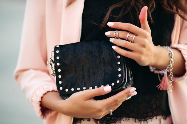 Жіночі руки з красивим лаком для нігтів і кільцями, що тримають маленький чорний мішок
. - Фото, зображення