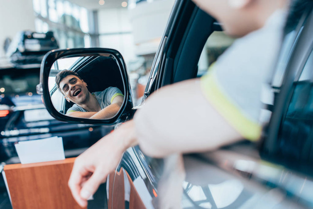 selective focus of successful happy man smiling while looking at mirror in automobile  - Photo, image