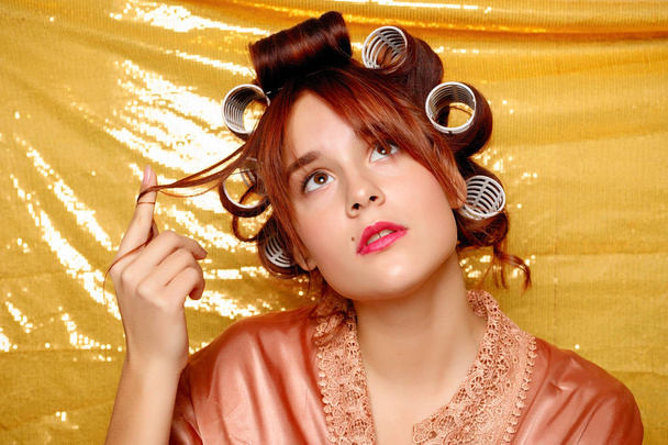 Menina bonita em encrespadores de cabelo isolado em ouro
 - Foto, Imagem