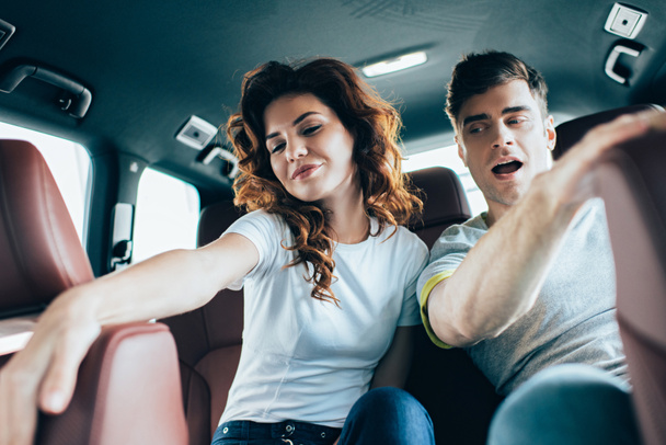 selective focus of attractive curly woman sitting near handsome man in automobile  - Φωτογραφία, εικόνα