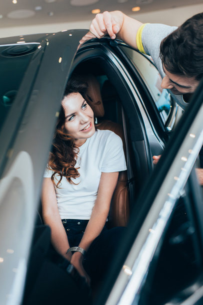 selective focus of attractive woman looking at man while sitting in automobile  - Foto, Bild