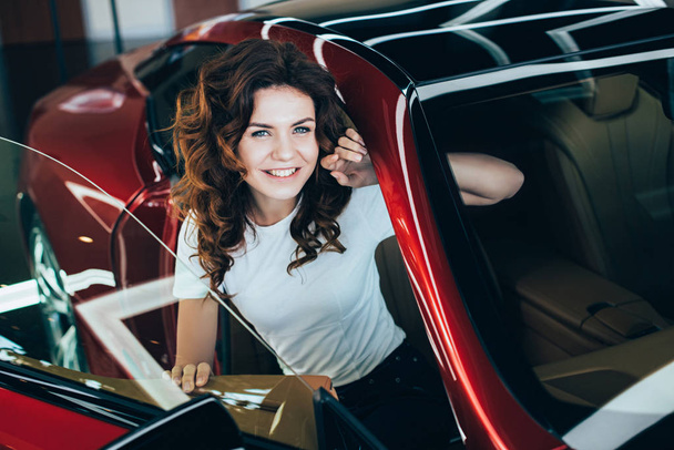 messa a fuoco selettiva di donna felice seduta nella nuova auto rossa e guardando la fotocamera
 - Foto, immagini