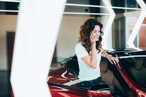 selective focus of smiling woman talking on smartphone while standing near new car - Foto, Imagem
