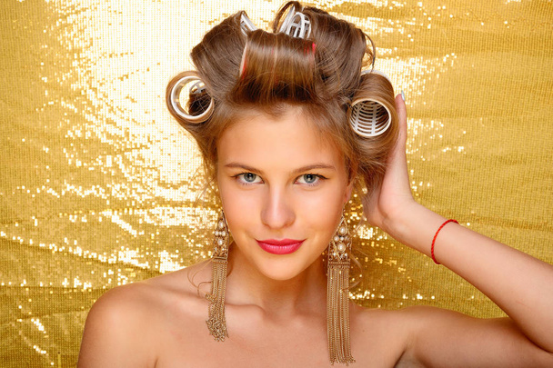 Beautiful girl in hair curlers isolated on gold - Valokuva, kuva