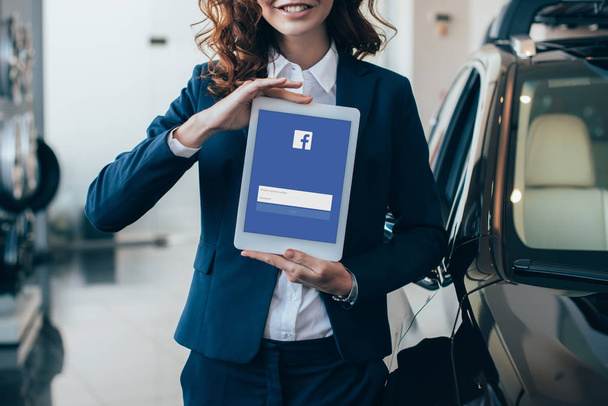 частичное представление предпринимательницы, держащей цифровой планшет с приложением facebook на экране
 - Фото, изображение