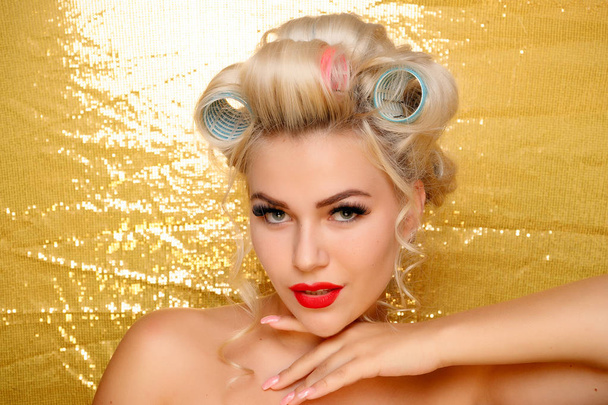 Beautiful girl in hair curlers isolated on gold - Photo, Image