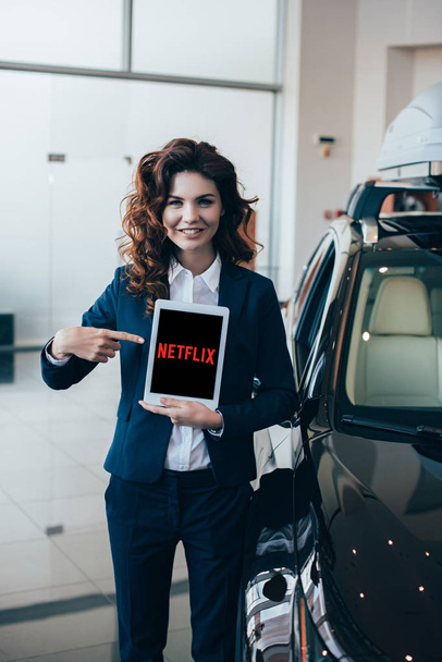 beautiful businesswoman pointing with finger at digital tablet with netflix app on screen - 写真・画像
