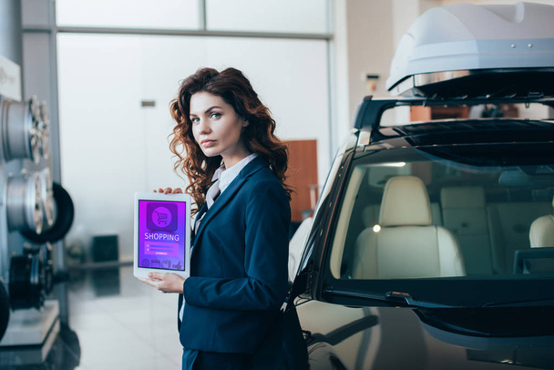 confident businesswoman holding digital tablet with shopping app on screen and looking at camera - Фото, зображення