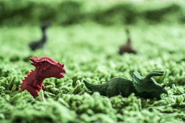 Hračky dinosauři ve vysoké trávě miniaturní divoký život - Fotografie, Obrázek