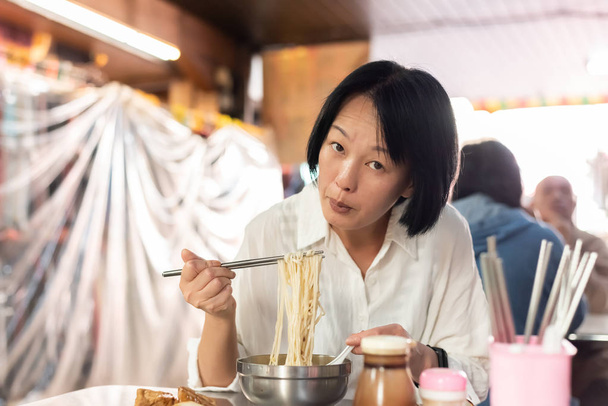 mujer asiática madura comer fideos
 - Foto, imagen